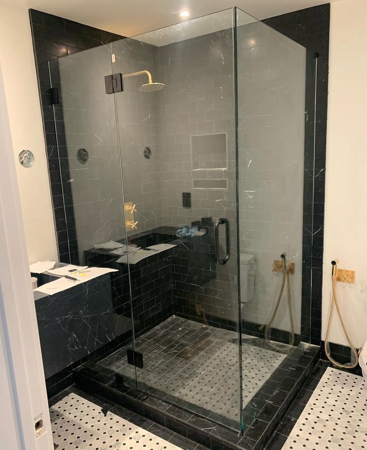 Black marble shower with corner glass enclosure