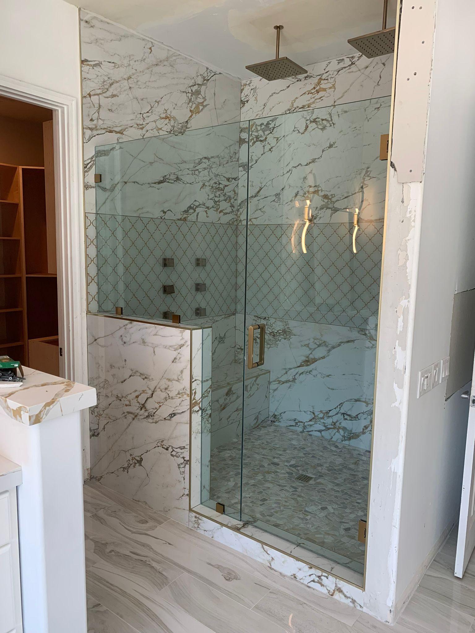Geometric patterned glass shower with marble surround